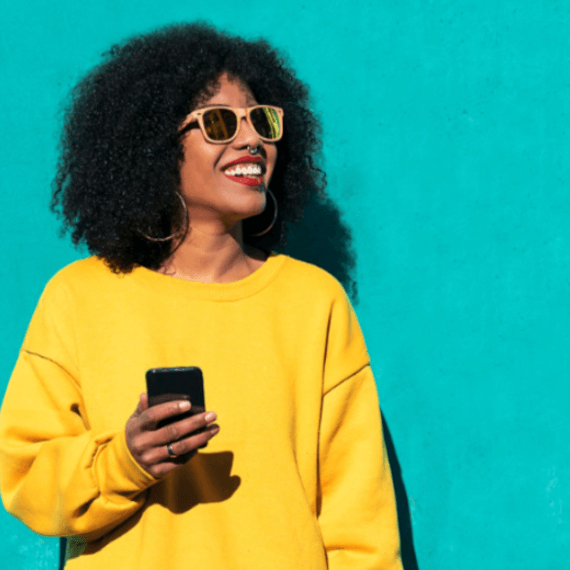 A female wearing a yellow sweatshirt with sunglasses and earrings.