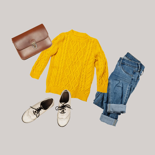 photo of laid out cloths: purse yellow sweater, jeans and white shoes.