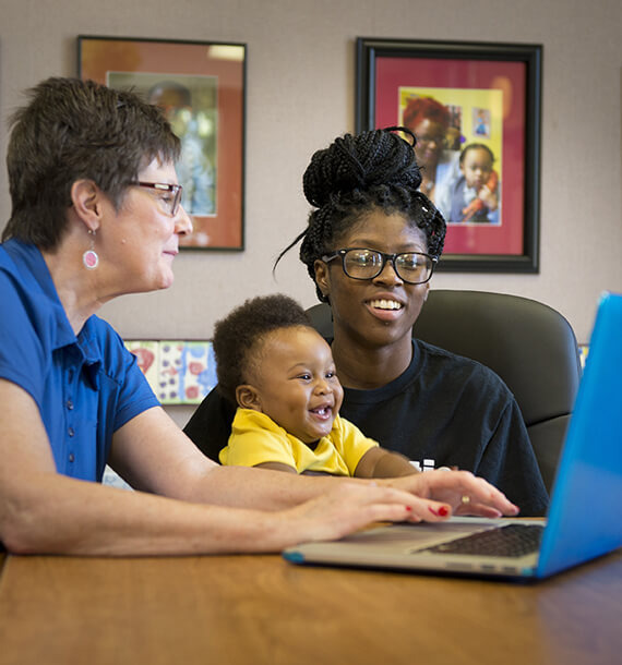 Photo of a goodwill employee meeting with a mother and baby.