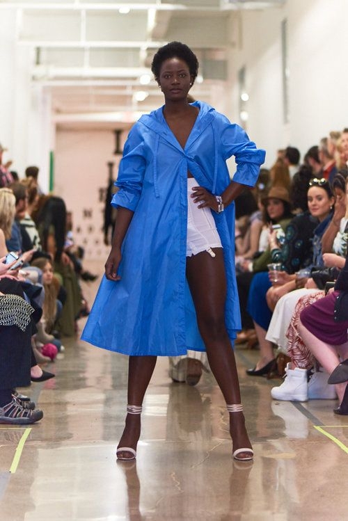 Young woman poses on runway wearing blue coat from Gina + Will
