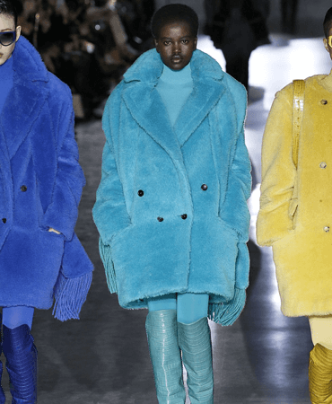 Photo of Adut Akech walking the runway at the max mara wearing a teal coat.