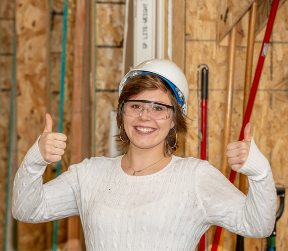 Participant wearing a construciton helmet smiling and giving two thumbs up.