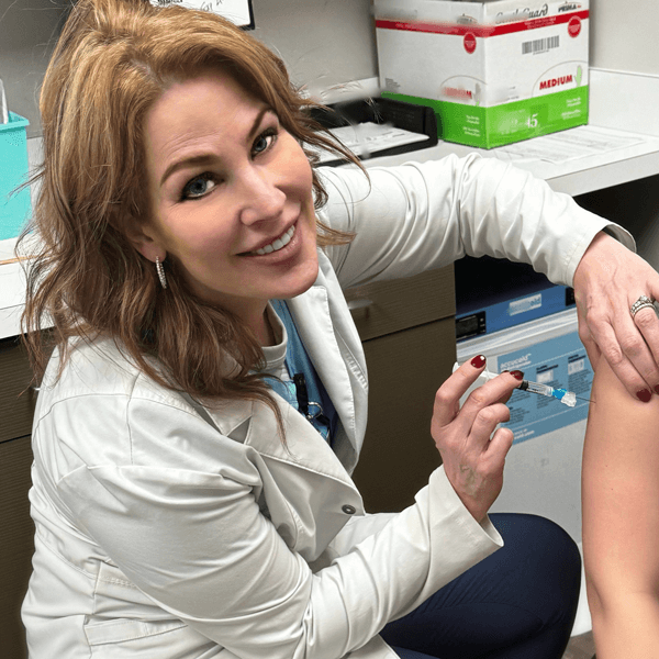 Danielle smiling and giving a patient a shot in the arm.