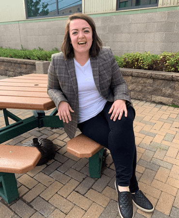 Photo of Maggie, GESMN Marketing Manager wearing a plaid blazer