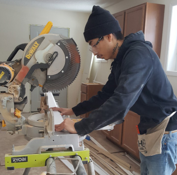Photo of Adrian using a miter saw.
