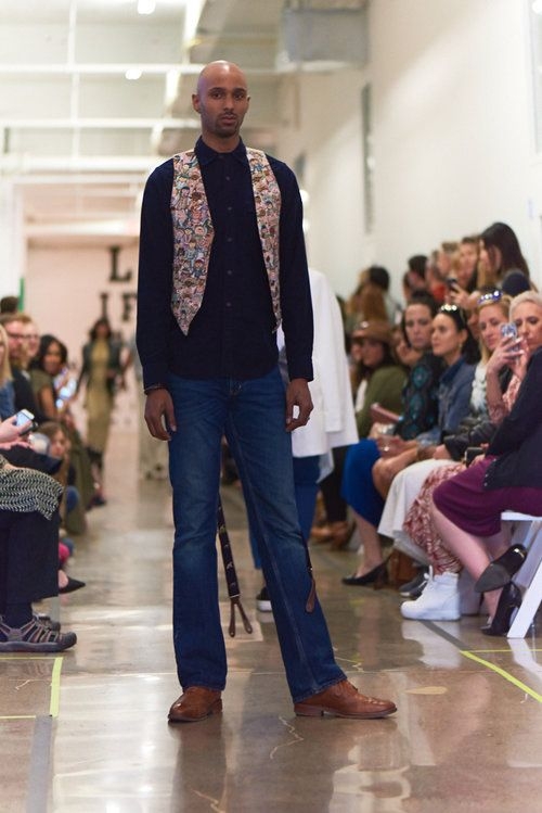 Young man poses on runway in jeans, button-up and vest from Gina + Will