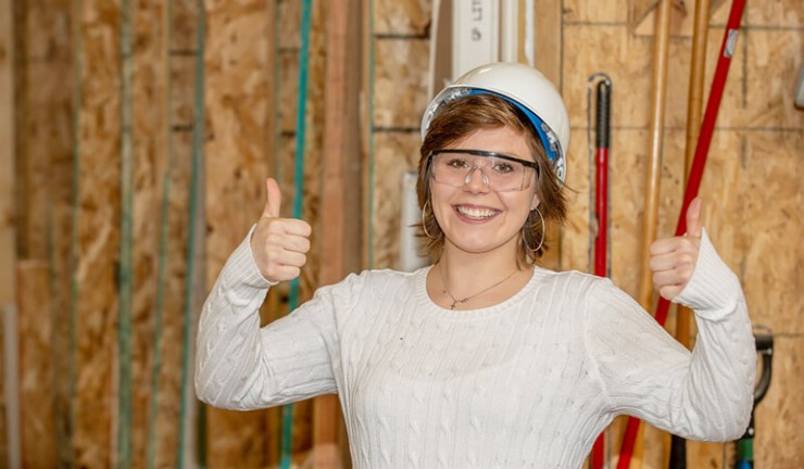 Photo of construction participant smiling with a hard hat on her head.