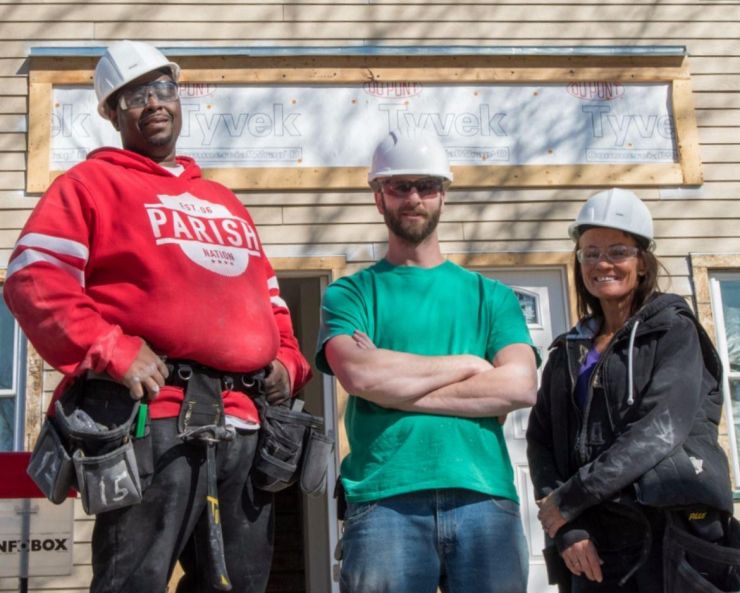 Construction participants and instructor in front of a duplex