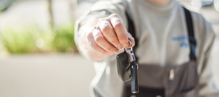 Photo of a person's hand with a car key extending out to hand you the keys.